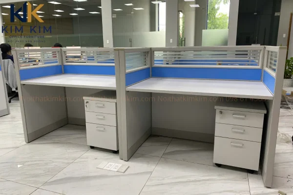 Cụm bàn làm việc 2 chỗ có vách ngăn xanh và hộc tủ cá nhân tại văn phòng Công ty Button Việt Nam.